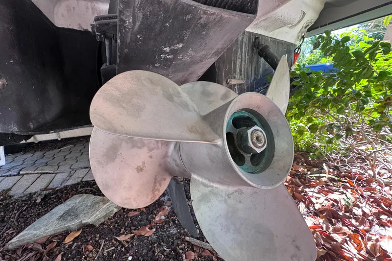 Slide: The Image of Close-up of a 2015 Regal 28 Express boat propeller, showing metal blades and surrounding foliage. - 74