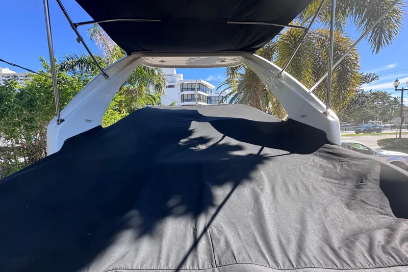 Slide: The Image of 2015 Regal 28 Express boat with black cover, surrounded by palm trees and buildings. - 81