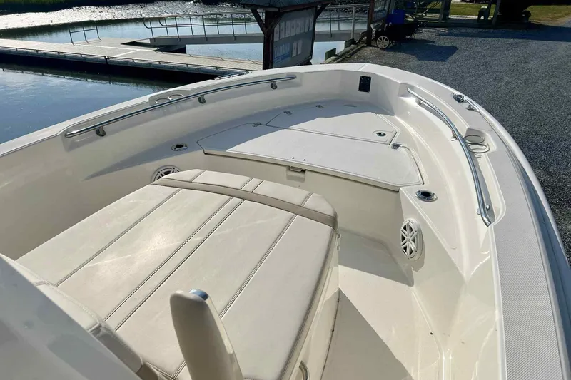 Slide: The Image of 2024 Boston Whaler 220 Dauntless boat interior with seating and storage, dockside view. - 10