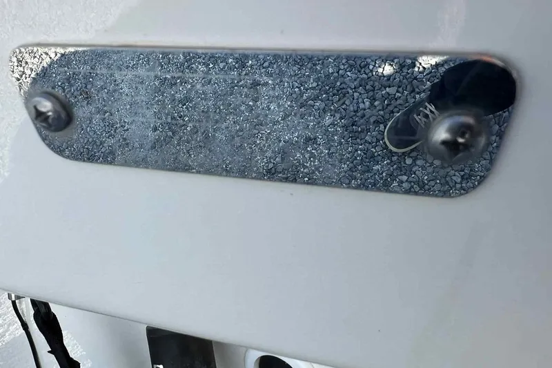 Slide: The Image of Reflective metal plate on 2024 Boston Whaler 220 Dauntless boat, showing gravel and shoe reflection. - 12