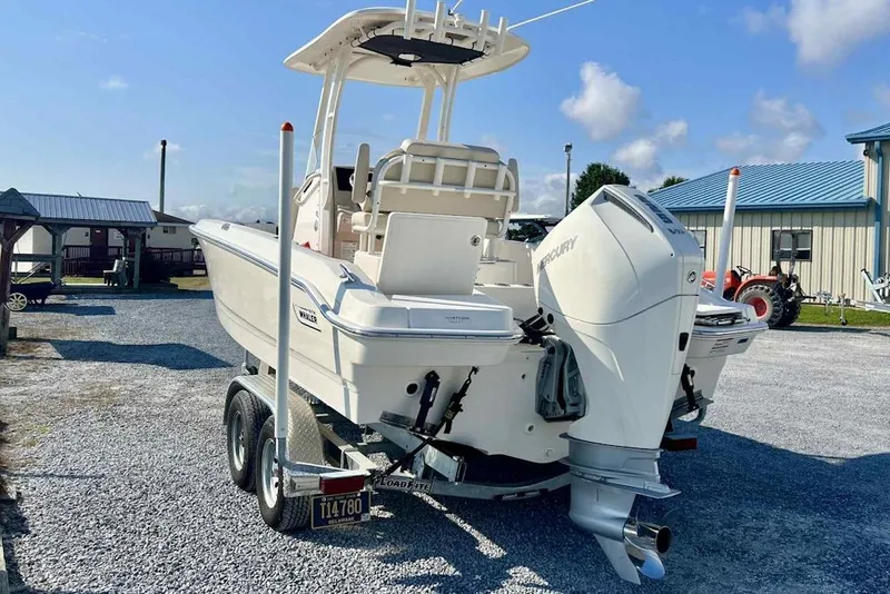 Slide: The Image of 2024 Boston Whaler 220 Dauntless boat on trailer, featuring Mercury outboard engine. - 2