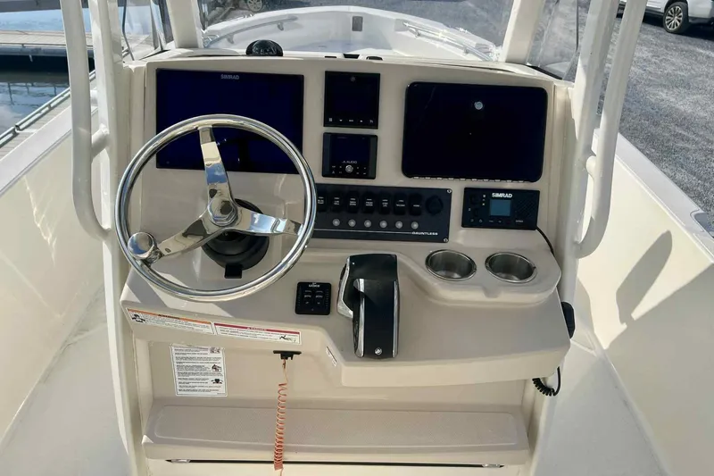 Slide: The Image of 2024 Boston Whaler 220 Dauntless boat console with steering wheel and navigation controls. - 5
