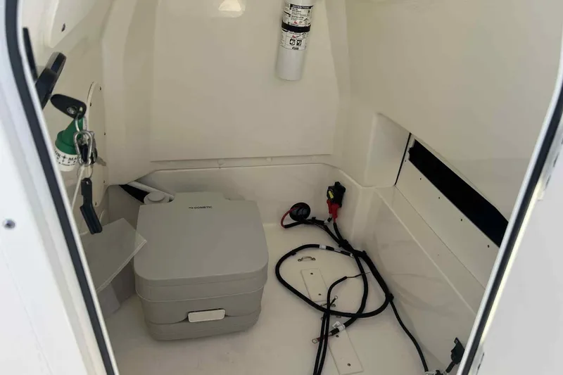 Slide: The Image of Interior of 2024 Boston Whaler 220 Dauntless boat, featuring a compact marine toilet. - 8