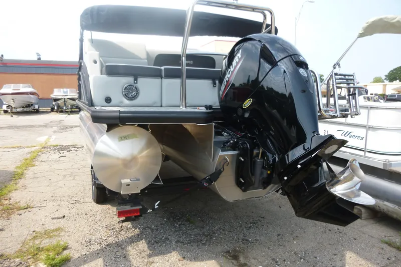 Slide: The Image of 2025 Harris pontoon boat with Mercury outboard motor, parked on a lot. - 7