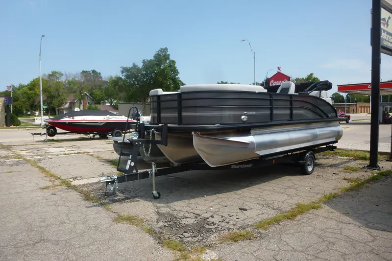 Slide: The Image of 2025 Harris pontoon boat on trailer in parking lot, sunny day. - 8