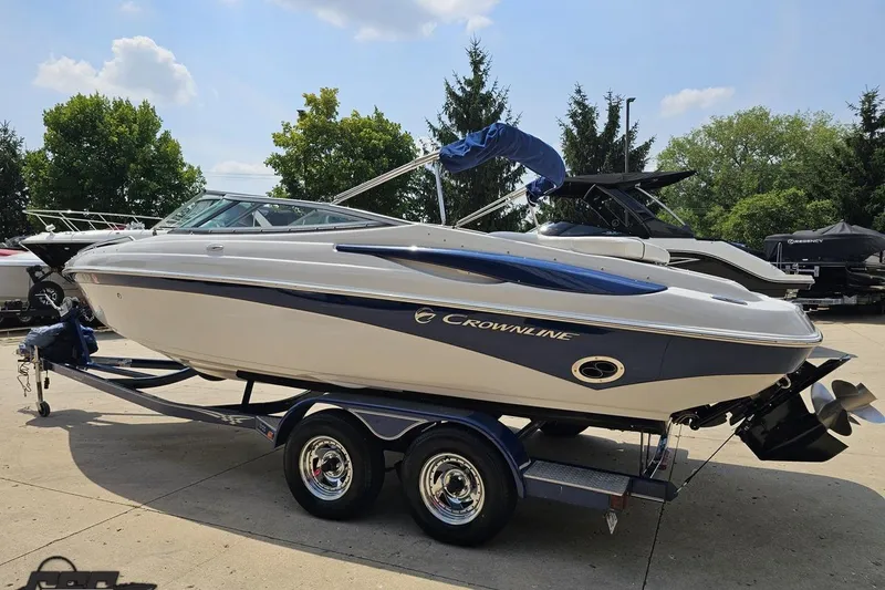 Slide: The Image of 2007 Crownline 23 SS boat on trailer, parked outdoors, surrounded by trees and other boats. - 25