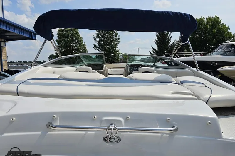 Slide: The Image of 2007 Crownline 23 SS boat with white seating and blue canopy under a clear sky. - 34