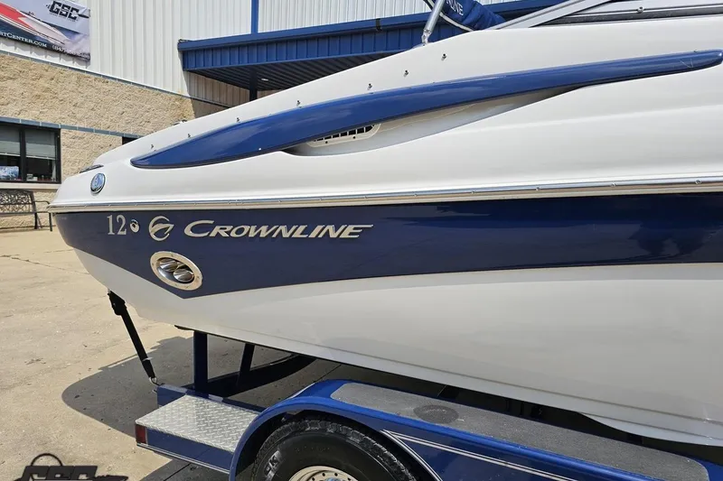 Slide: The Image of 2007 Crownline 23 SS boat on trailer, blue and white exterior, parked outside building. - 6