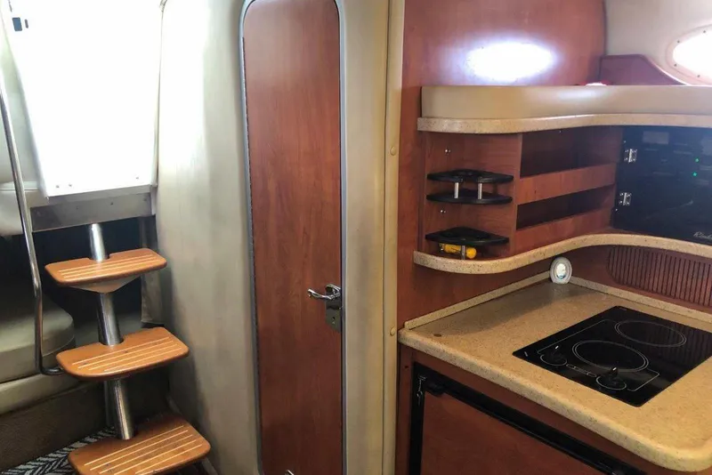 Slide: The Image of 2006 Rinker 342 Express Cruiser interior with wooden cabinetry and compact kitchen area. - 21