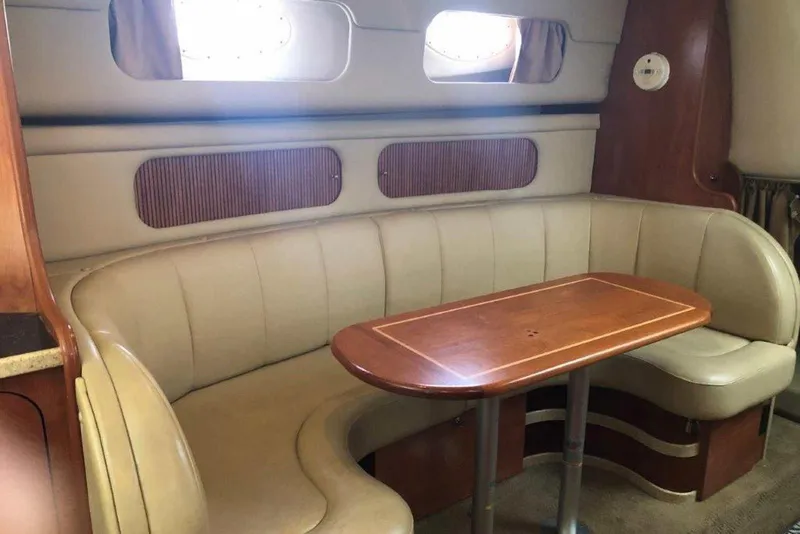 Slide: The Image of 2006 Rinker 342 Express Cruiser interior with beige seating and wooden table. - 24