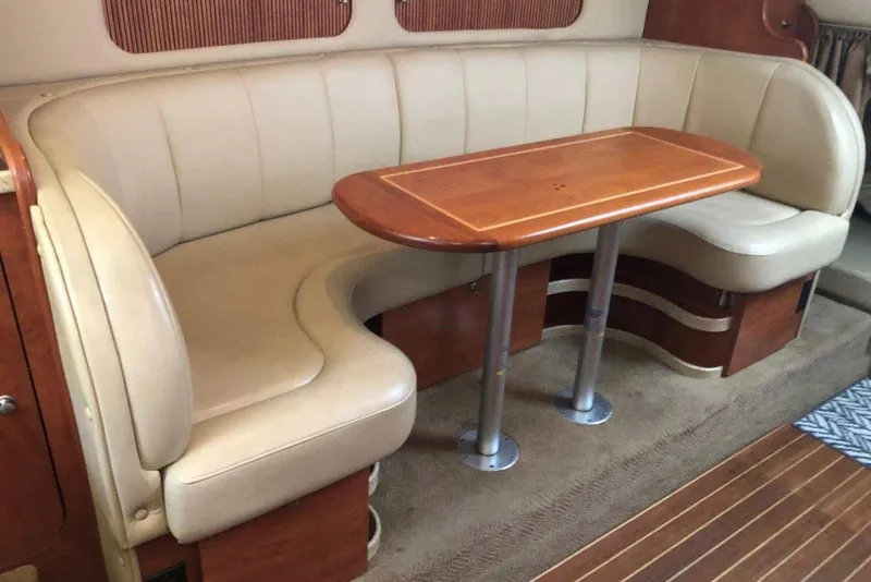 Slide: The Image of 2006 Rinker 342 Express Cruiser interior with beige leather seating and wooden table. - 25