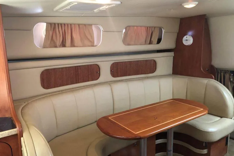 Slide: The Image of 2006 Rinker 342 Express Cruiser interior with beige seating and wooden table. - 26