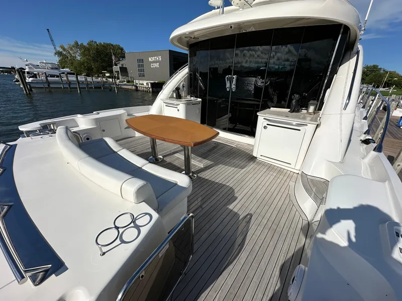 Slide: The Image of 2009 Sea Ray 60 Sundancer yacht with spacious deck, seating, and table, docked at marina. - 2