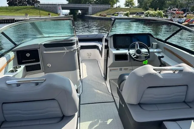 Slide: The Image of 2026 Regal LS9 boat interior with modern dashboard and seating, docked by a scenic waterway. - 1