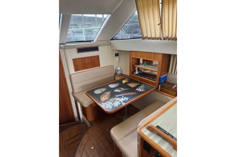 Slide: The Image of 2005 Carver 33 Super Sport interior with dining area, featuring a decorative table and beige seating. - 15