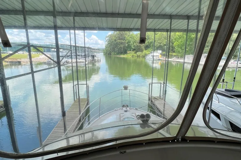 Slide: The Image of 2005 Carver 33 Super Sport yacht on calm water, surrounded by trees and clear sky. - 4