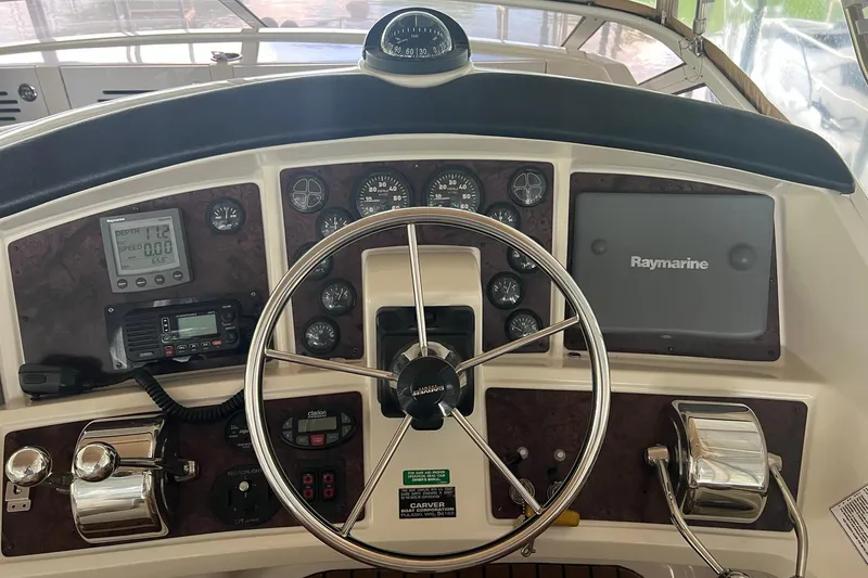 Slide: The Image of 2005 Carver 33 Super Sport yacht docked, viewed from the interior helm, overlooking calm waters. - 6