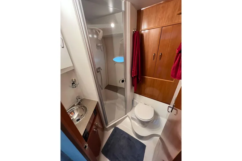 Slide: The Image of 2005 Carver 33 Super Sport bathroom with shower, sink, and wooden cabinetry. - 16