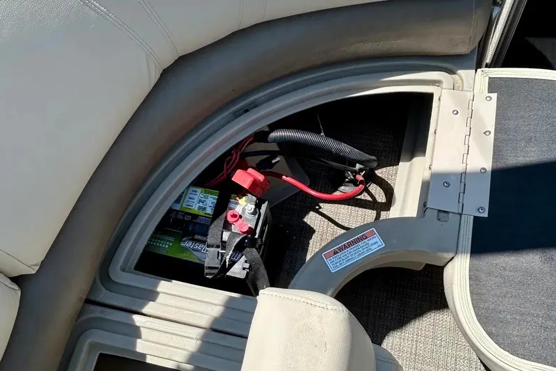 Slide: The Image of 2017 Starcraft CX 23 RE boat battery compartment with wiring and warning label. - 19