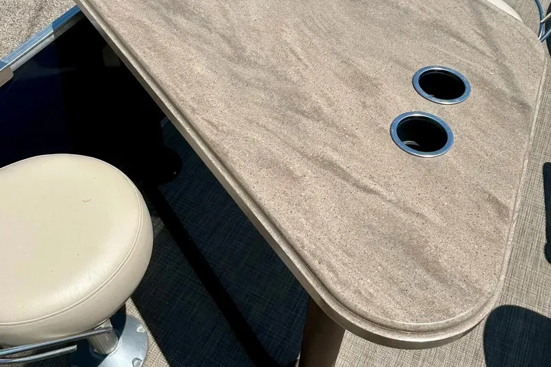 Slide: The Image of 2017 Starcraft CX 23 RE boat interior with beige seat and table with cup holders. - 30