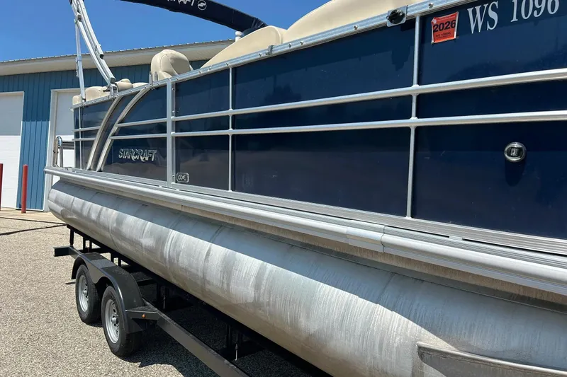 Slide: The Image of 2017 Starcraft CX 23 RE pontoon boat on trailer, parked outside a blue building. - 4
