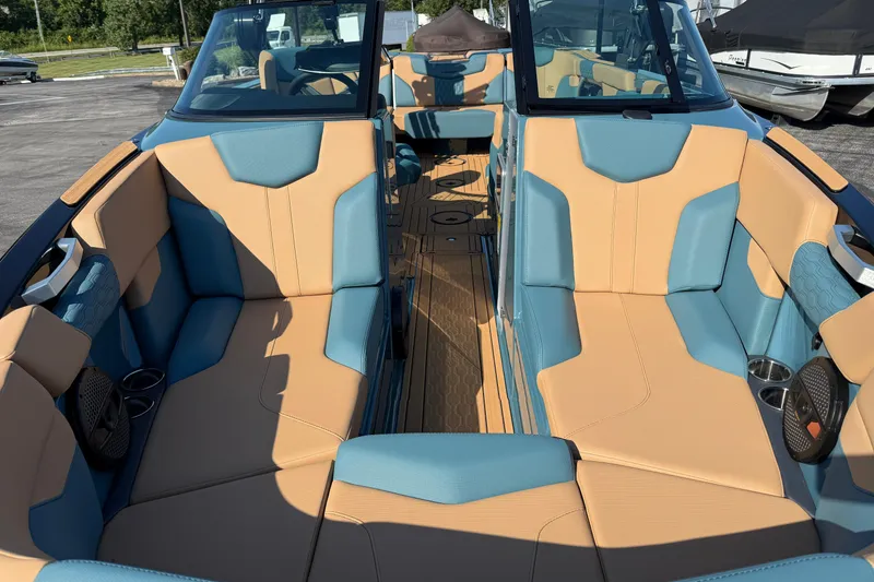 Slide: The Image of 2025 MasterCraft XT24 boat interior with tan and blue seating, docked outdoors. - 10