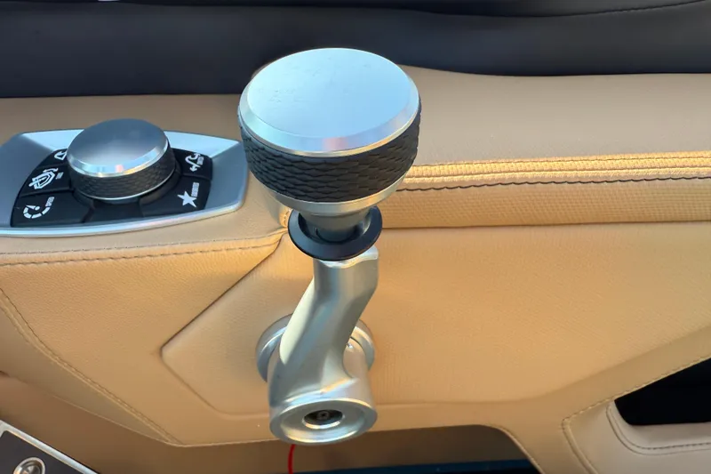 Slide: The Image of 2025 MasterCraft XT24 boat throttle and control panel on beige interior. - 24