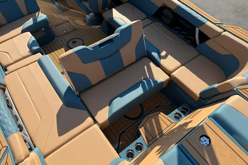 Slide: The Image of 2025 MasterCraft XT24 boat interior with tan and blue seating, cup holders, and teak flooring. - 36