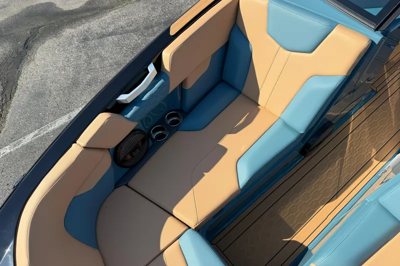 Slide: The Image of 2025 MasterCraft XT24 boat interior with tan and blue seating, cup holders, and speaker. - 38