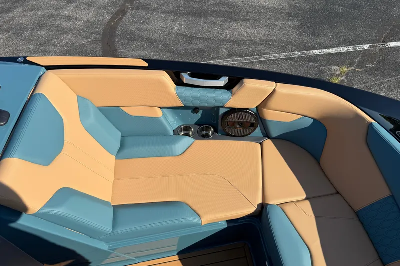 Slide: The Image of 2025 MasterCraft XT24 boat interior with tan and blue seating, cup holders, and speaker. - 39