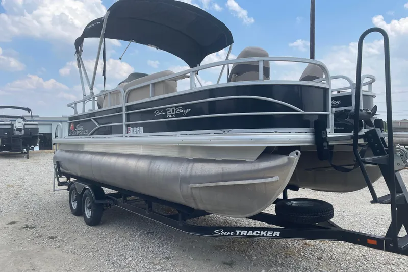 Slide: The Image of 2016 Sun Tracker Fishin' Barge 20 DLX pontoon boat on trailer, under blue sky. - 4