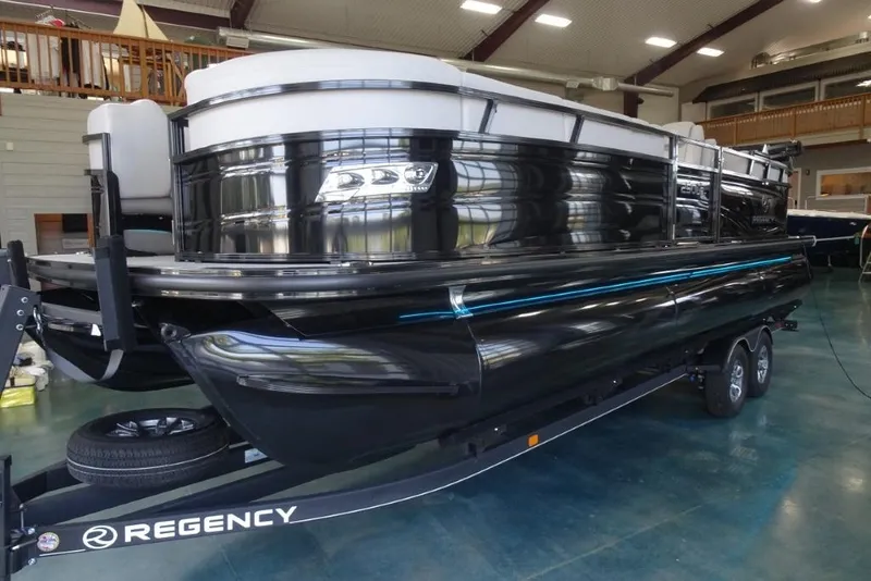 Slide: The Image of 2024 Regency 250 LE3 pontoon boat in showroom, sleek black design on trailer. - 11