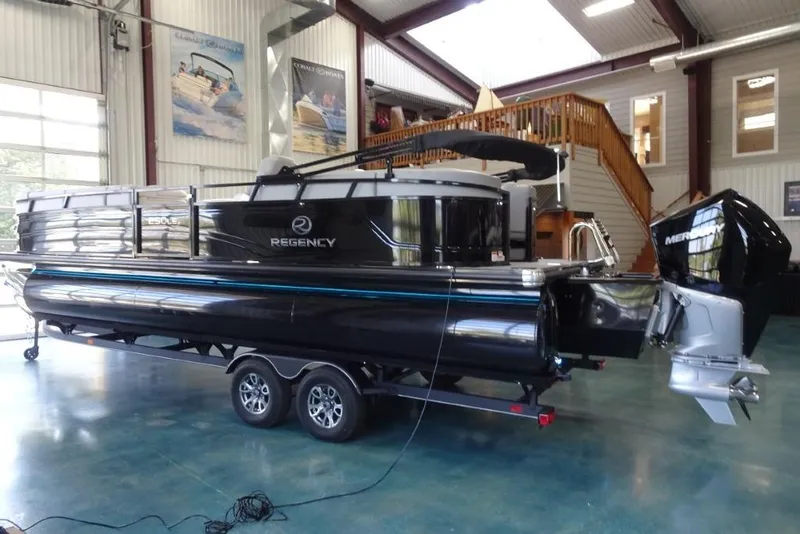 Slide: The Image of 2024 Regency 250 LE3 pontoon boat displayed indoors on a trailer. - 9