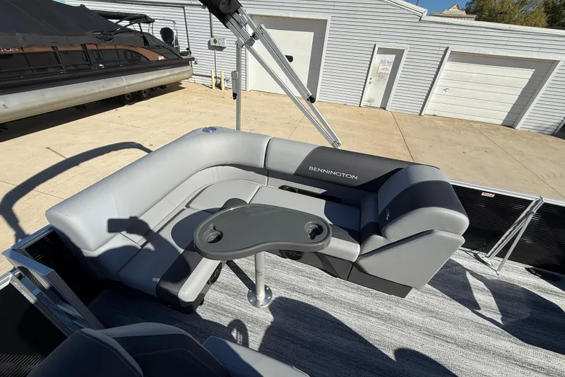 Slide: The Image of 2026 Bennington 168 SF Electric pontoon boat with gray seating and table, parked outdoors. - 19
