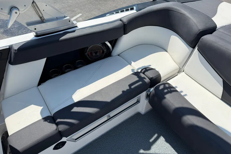 Slide: The Image of 2019 MasterCraft XT22 boat interior with black and white seating, cup holders, and speaker. - 20
