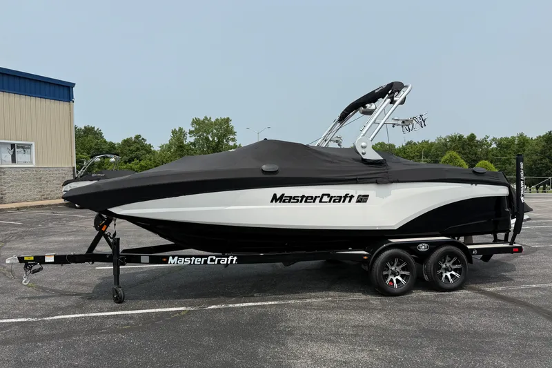 Slide: The Image of 2019 MasterCraft XT22 boat with cover on trailer, parked outdoors. - 27