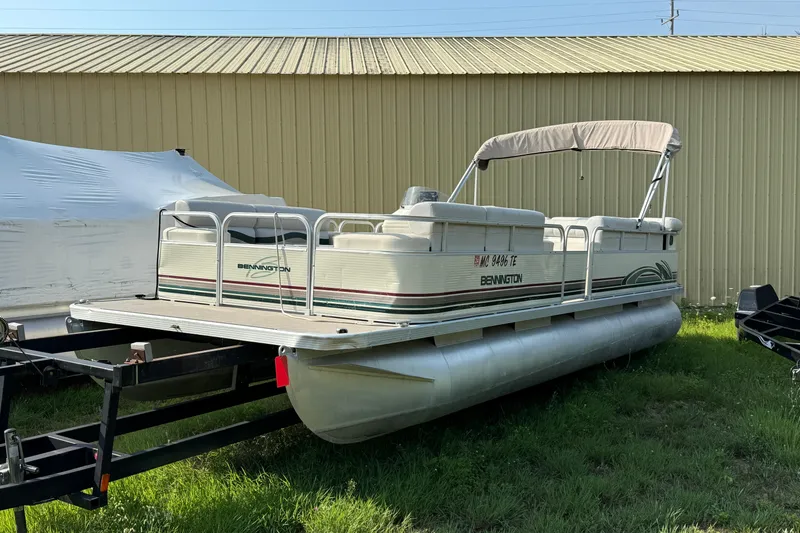 Slide: The Image of 1999 Bennington Twin-Toon pontoon boat on trailer, parked beside a building. - 1