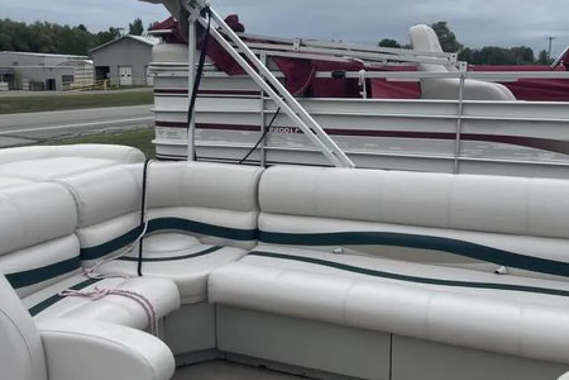 Slide: The Image of 1999 Bennington twin-toon boat with white seating and green accents, docked outdoors. - 12