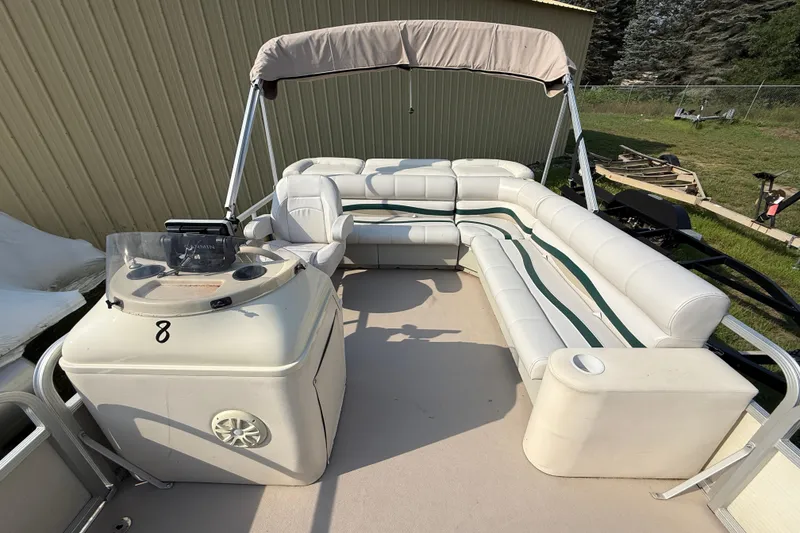 Slide: The Image of 1999 Bennington Twin-Toon pontoon boat with white seating and canopy, parked outdoors. - 19