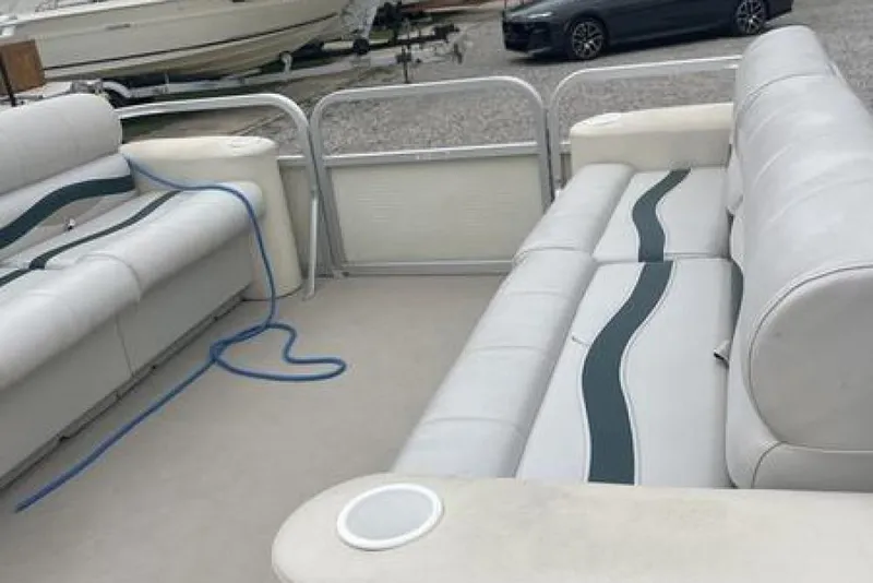 Slide: The Image of Interior of a 1999 Bennington twin-toon boat with white seating and blue accents. - 6