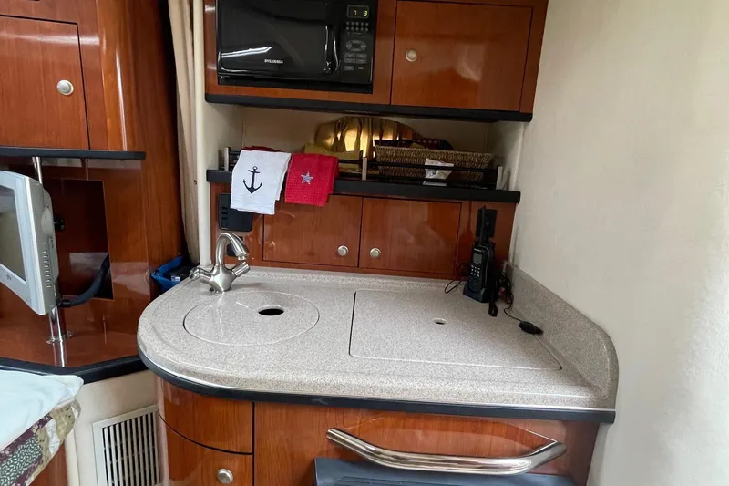 Slide: The Image of 2007 Sea Ray 290 Sundancer interior with kitchenette, featuring wood cabinetry and modern appliances. - 12