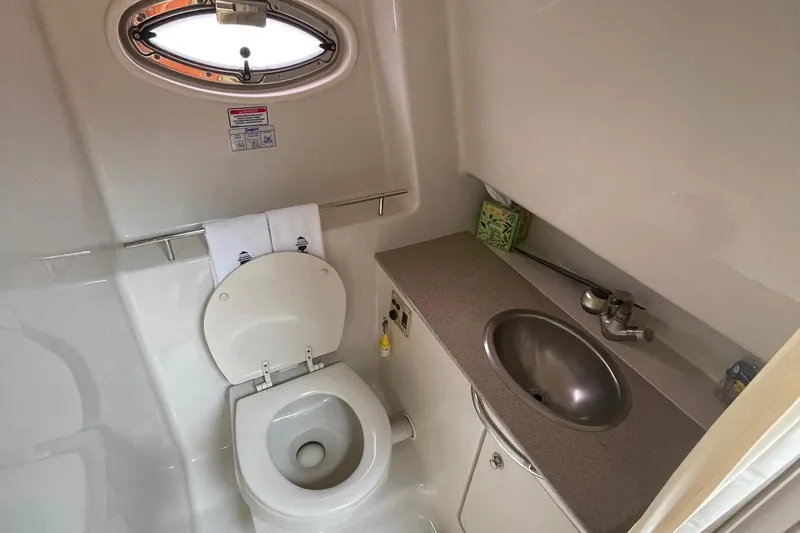 Slide: The Image of 2007 Sea Ray 290 Sundancer bathroom with toilet, sink, and porthole window. - 16