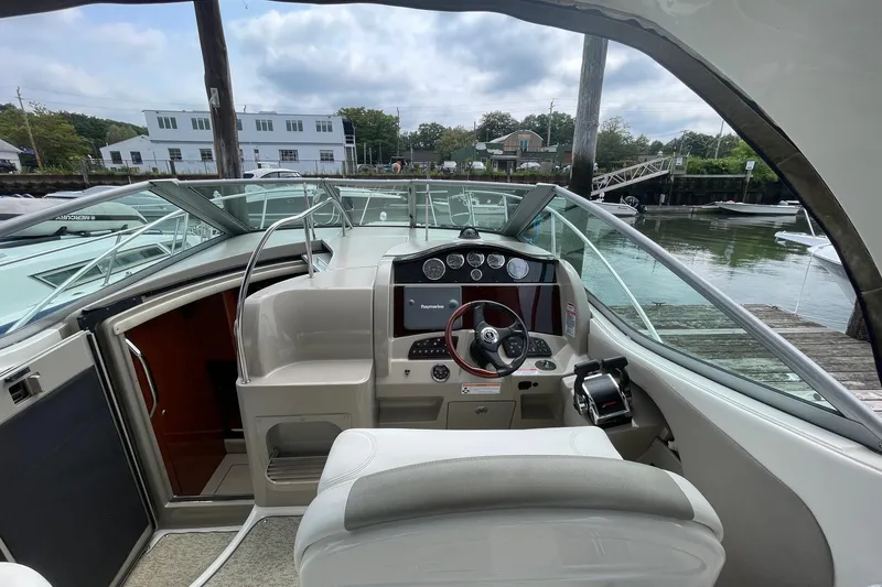 Slide: The Image of 2007 Sea Ray 290 Sundancer helm with modern controls, docked by a serene waterfront. - 9