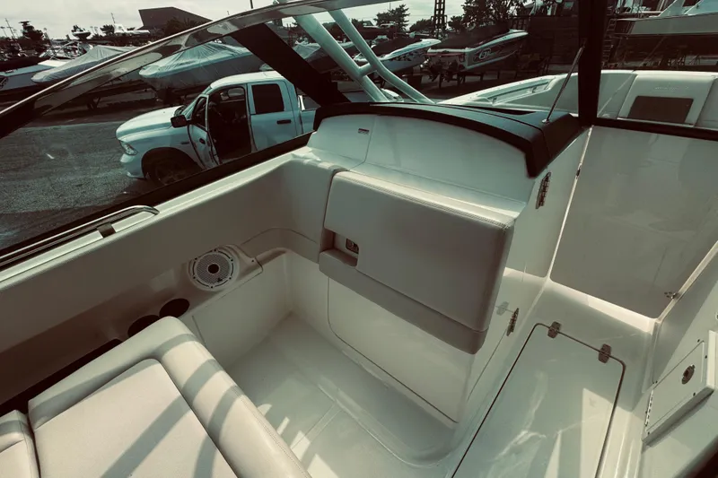 Slide: The Image of 2020 Boston Whaler 270 Vantage interior with seating and storage, docked near vehicles. - 25