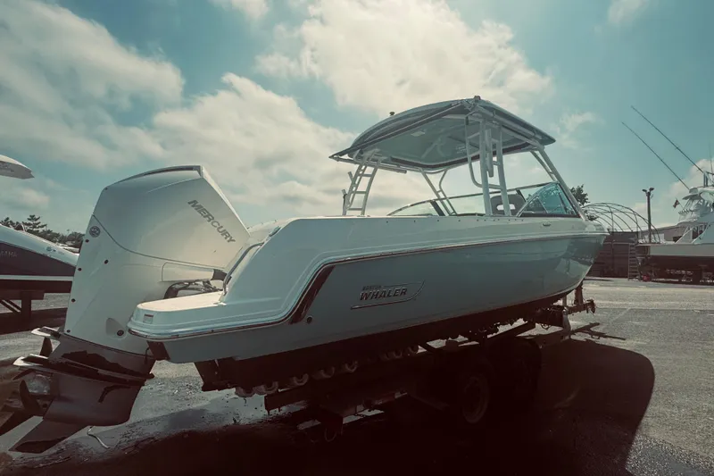 Slide: The Image of 2020 Boston Whaler 270 Vantage boat with Mercury engine, docked under a cloudy sky. - 3