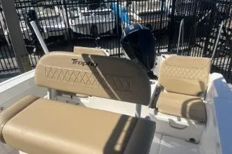 Slide: The Image of 2022 Trophy T22 boat interior with beige seating and motor, in a marina setting. - 6