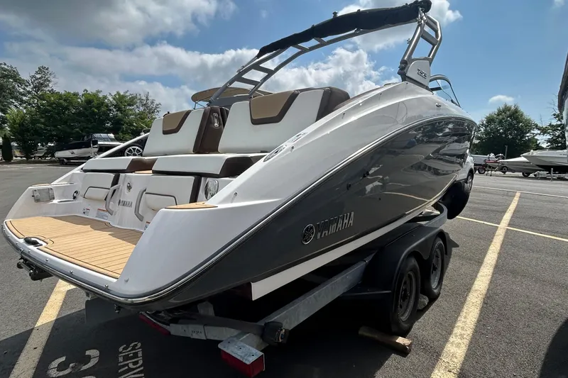 Slide: The Image of 2021 Yamaha Boats 252S on trailer, sleek design, parked outdoors under blue sky. - 1