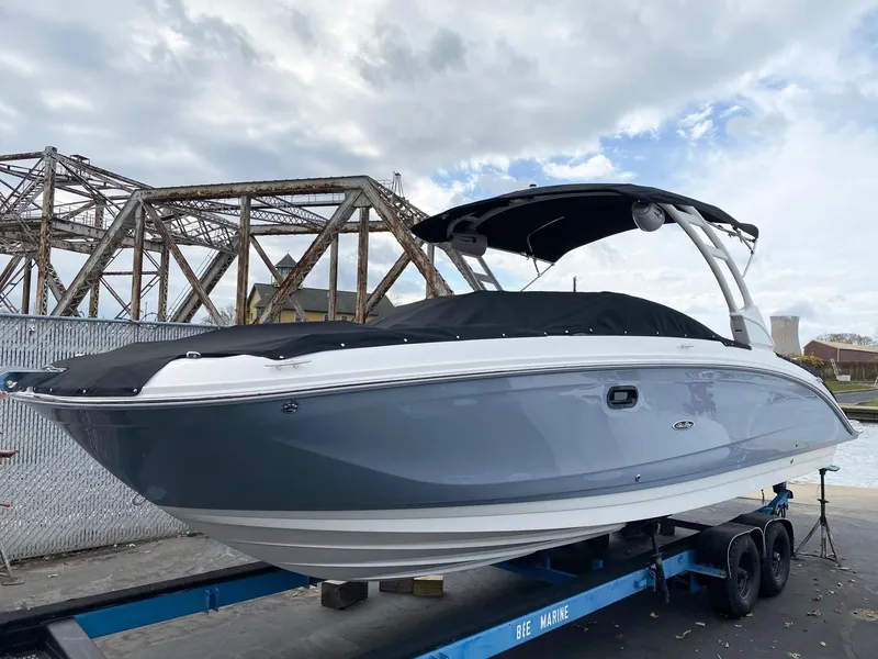The Image of 2021 Sea Ray SDX 290 boat on trailer, under cloudy sky near industrial bridge. - 0
