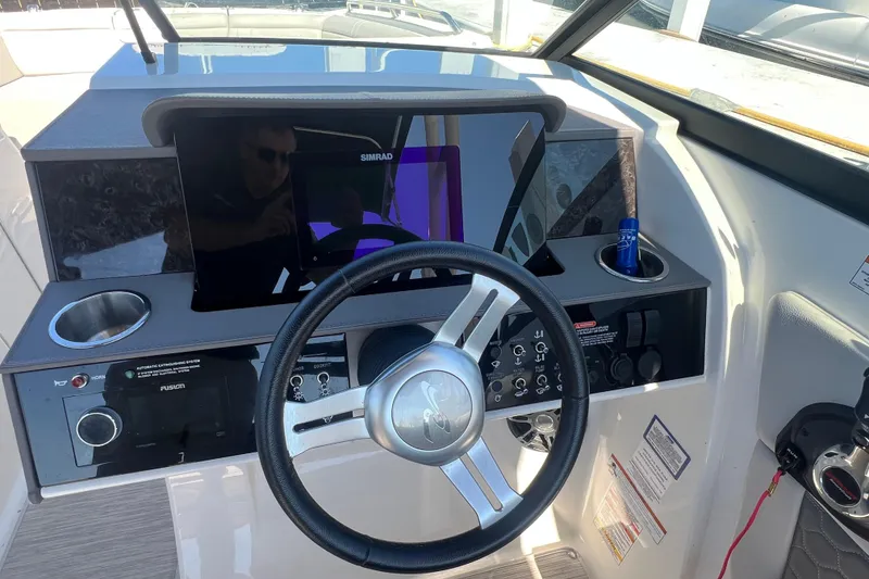 Slide: The Image of 2021 Sea Ray SDX 290 helm with steering wheel, Simrad display, and control panel. - 2