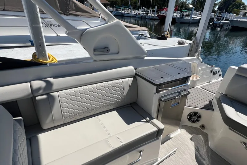 Slide: The Image of 2021 Sea Ray SDX 290 boat interior with seating and kitchenette, docked at marina. - 9